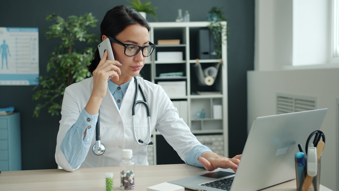 Sesame Online Doctor: Full Review and Comparison 7 Doctor on phone, working on laptop in office.